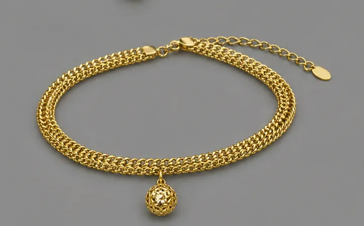 Double gold chain bracelet with an openwork ball charm